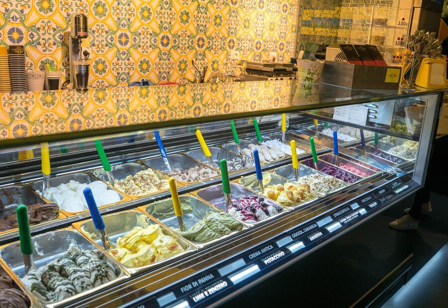 Display of colorful gelato flavors in metal trays at a gelateria