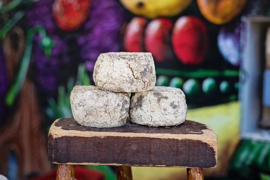 Blocks of artisan French cheese stacked at an outdoor farmers market