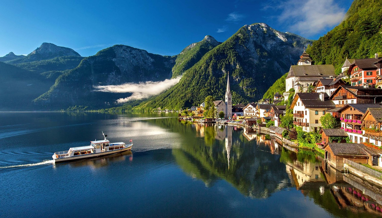 Hallstatt village with colorful buildings a church tower and boats on the lake in summer