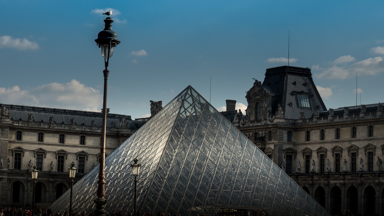 The Louvre glass pyramid and a lamp post at dusk with the museum building in the background