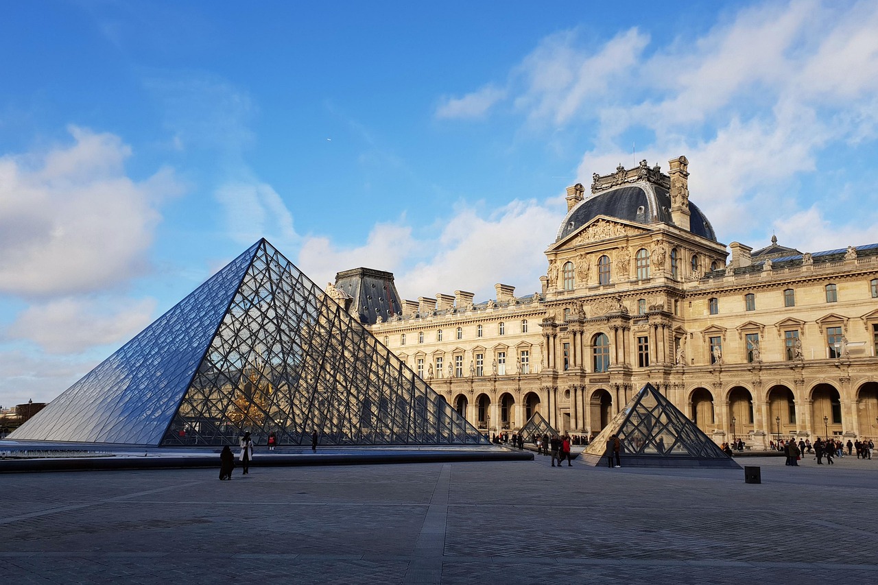 The Louvre Museum building with its iconic glass pyramid entrance and reflecting pool