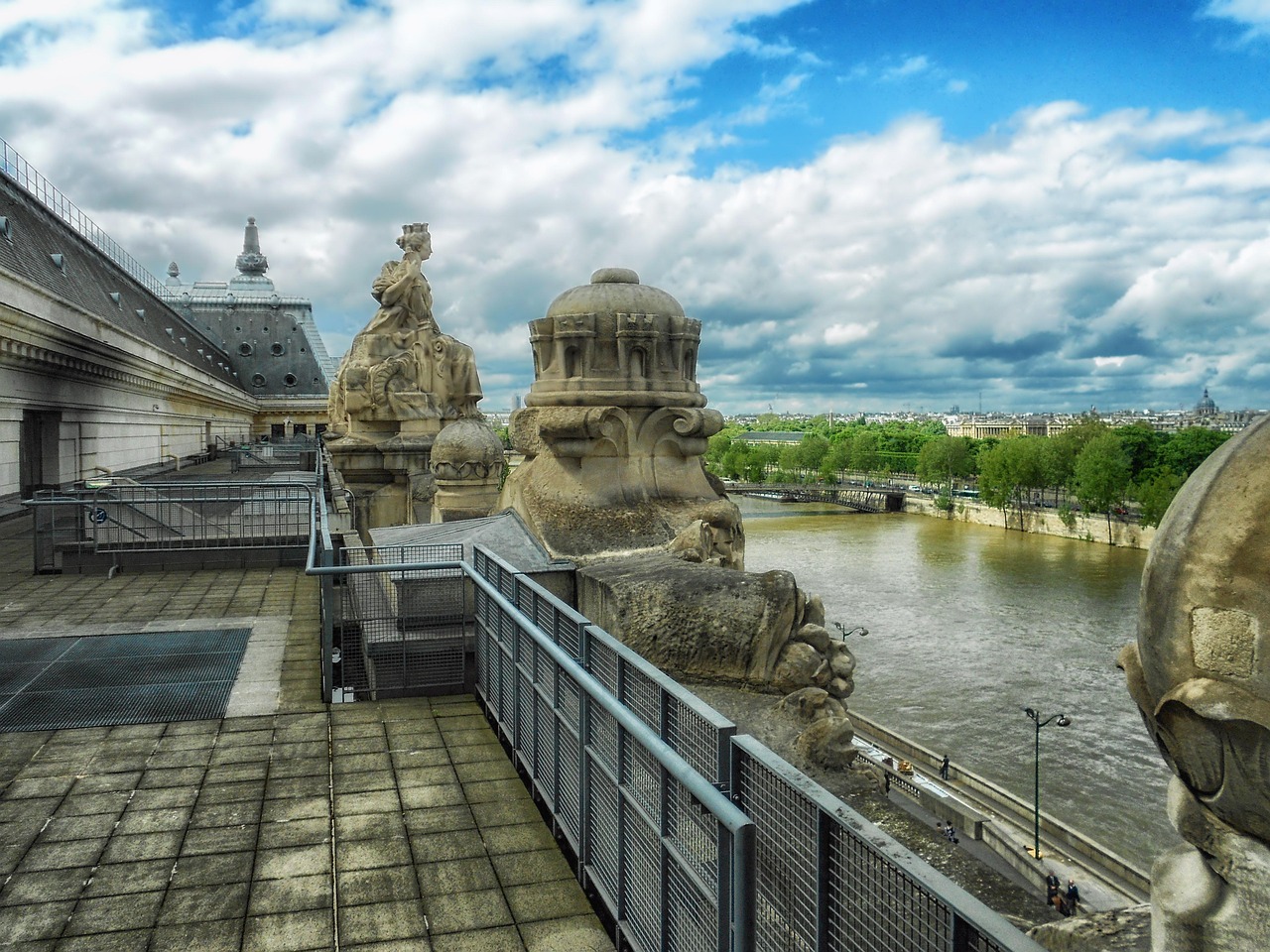 The Musee dOrsay building seen from across the Seine River with sculptures and cloudy sky