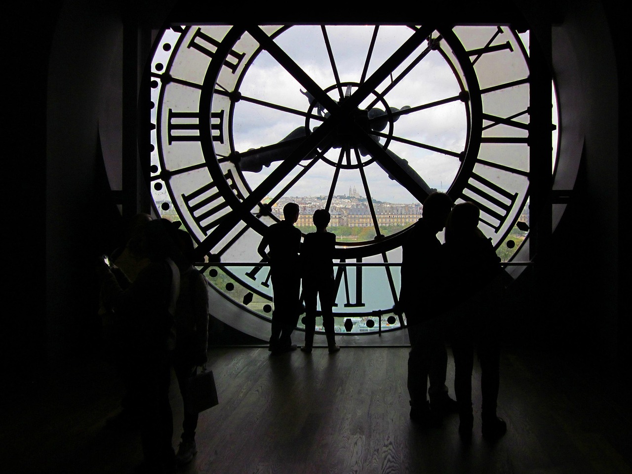 The iconic golden clock face at Musee dOrsay with Montmartre visible through it