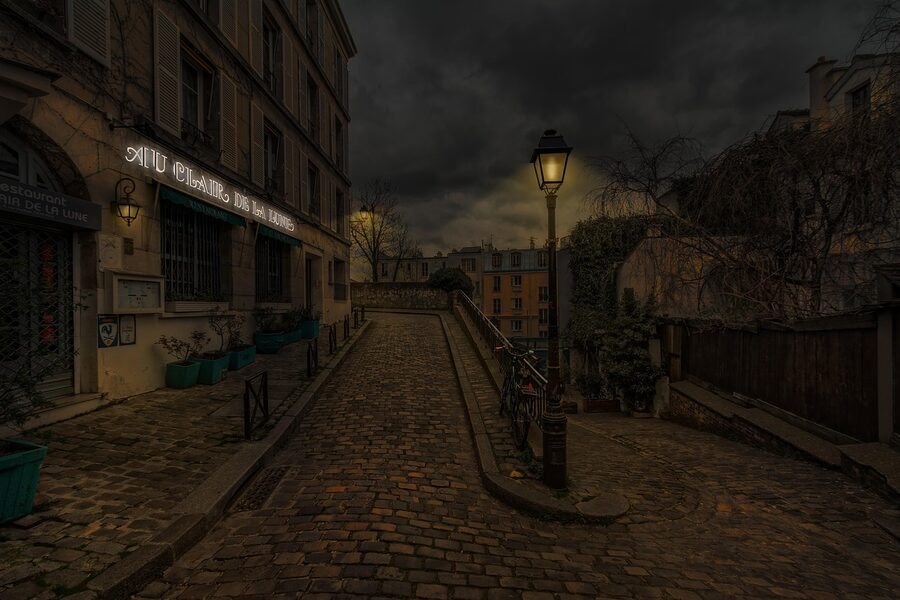 A quiet Paris street at night lit by warm streetlights
