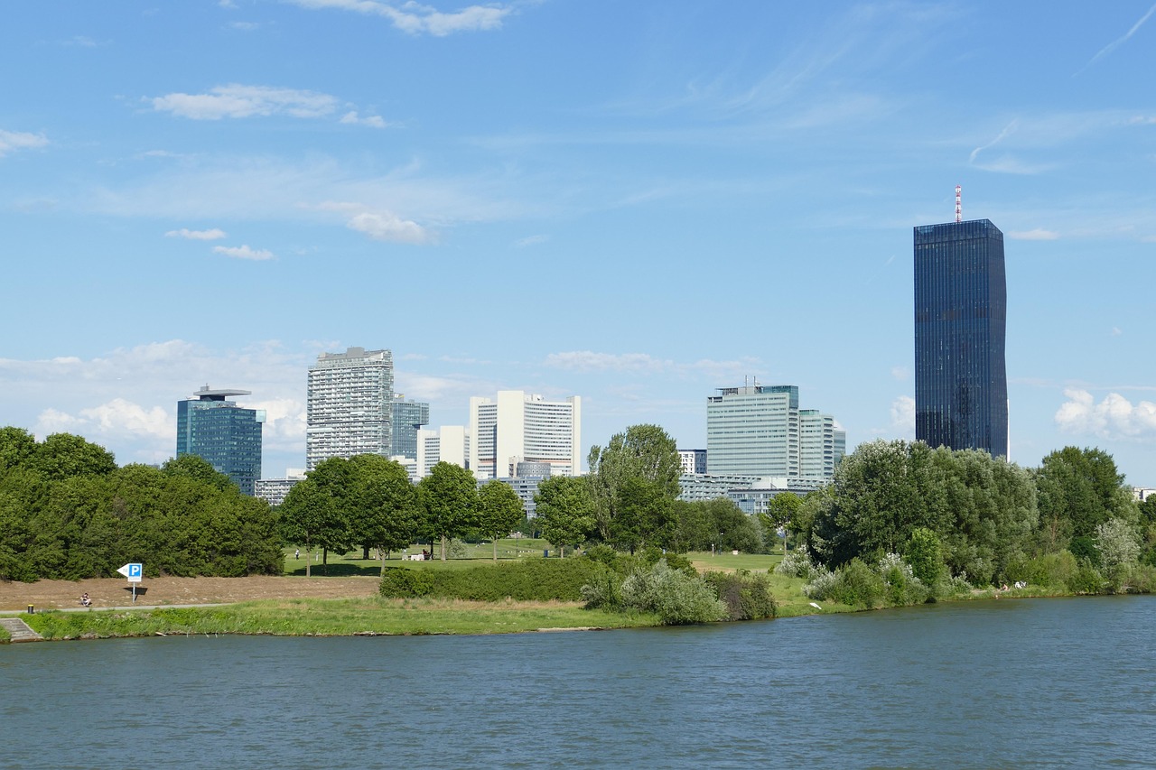 Panoramic view of Vienna along the Danube River with modern skyscrapers and a river cruise ship