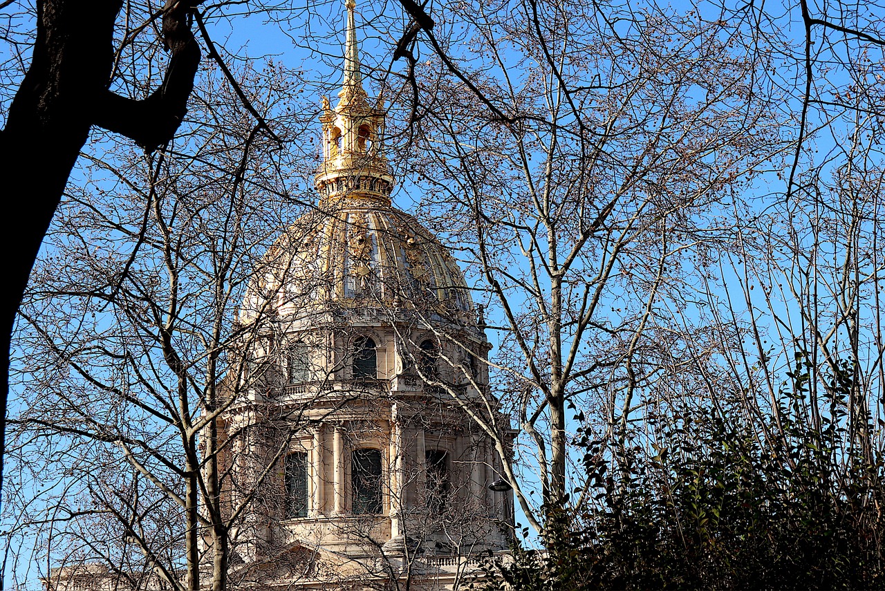 The gilded dome of Les Invalides against blue sky with winter trees in foreground