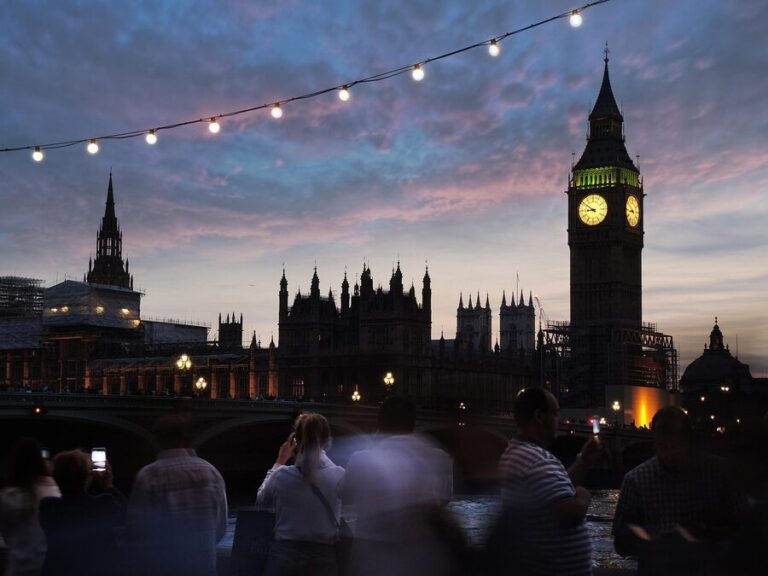 Big Ben and the Houses of Parliament lit up at night with crowds on Westminster Bridge