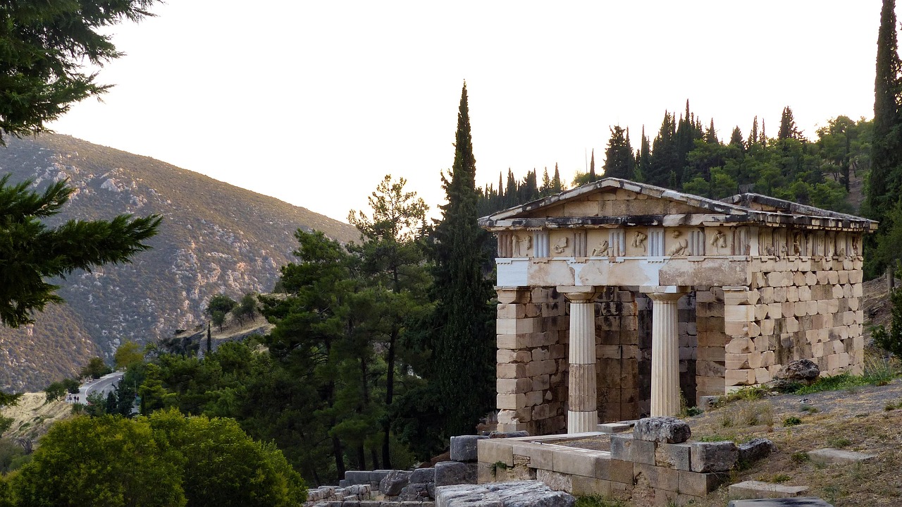 Treasury of the Athenians ruins at Delphi with olive valley and mountains in background