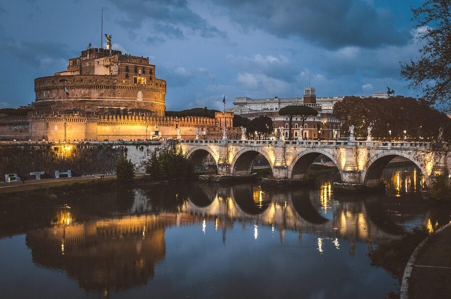 Castel Sant'Angelo at night illuminated and reflected in the Tiber River with the bridge in view