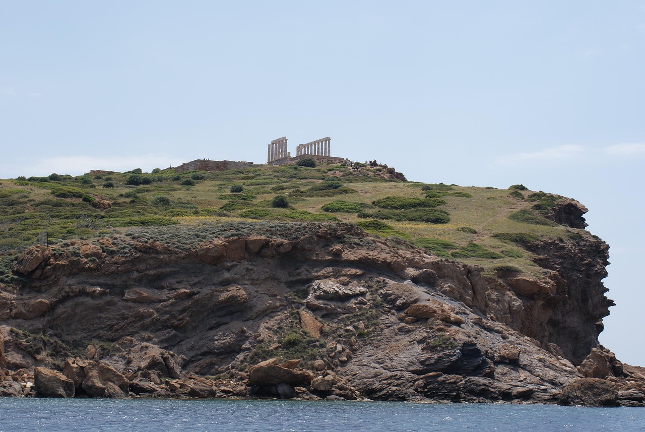 Ruins of an ancient Greek temple with columns standing against the blue Aegean Sea