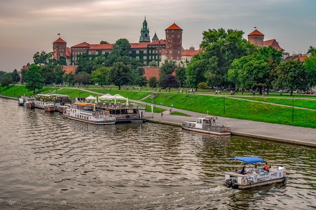 Tour boats and a floating restaurant on the Vistula River beneath Wawel Castle in Krakow