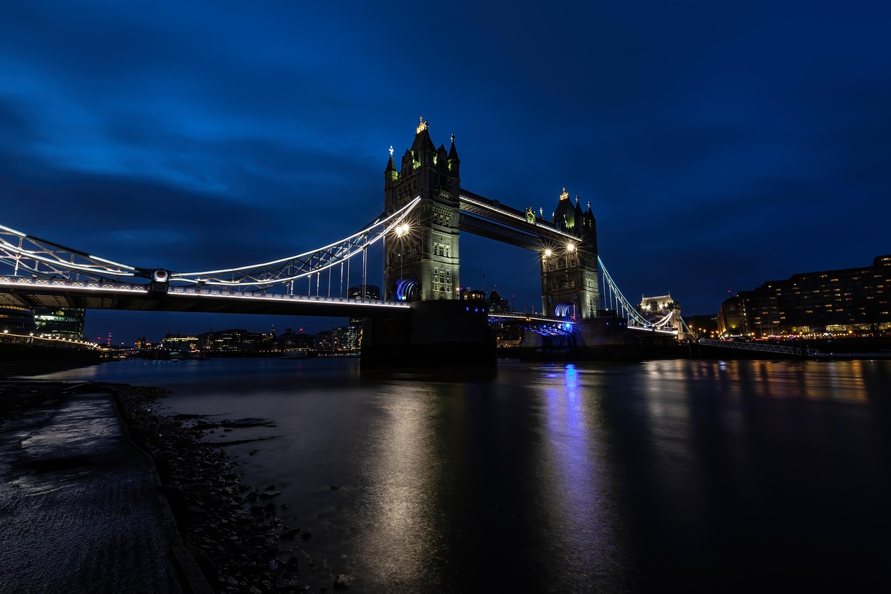 Tower Bridge in London lit up at night reflecting in the River Thames