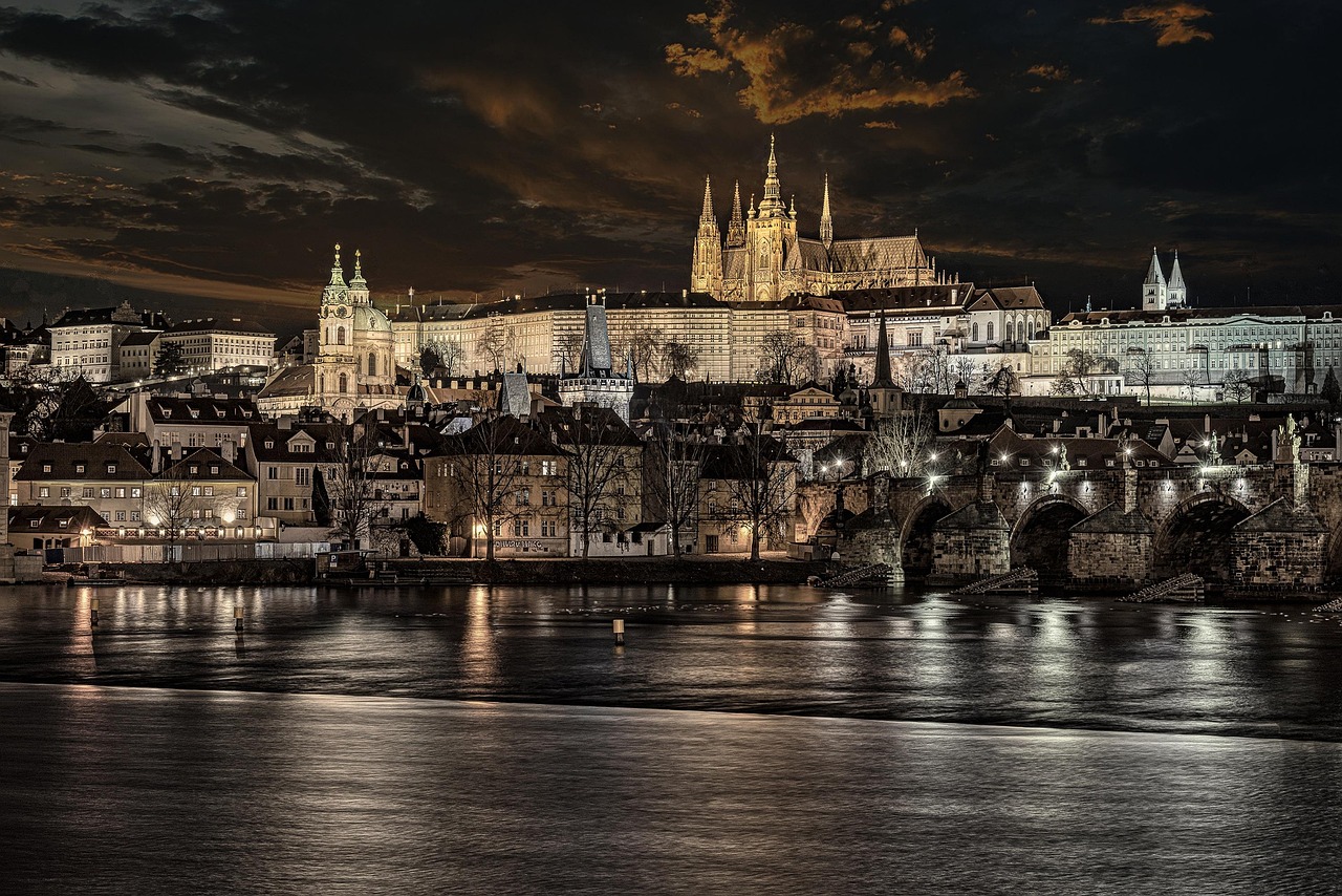 Charles Bridge and Prague Castle illuminated at night with river reflections