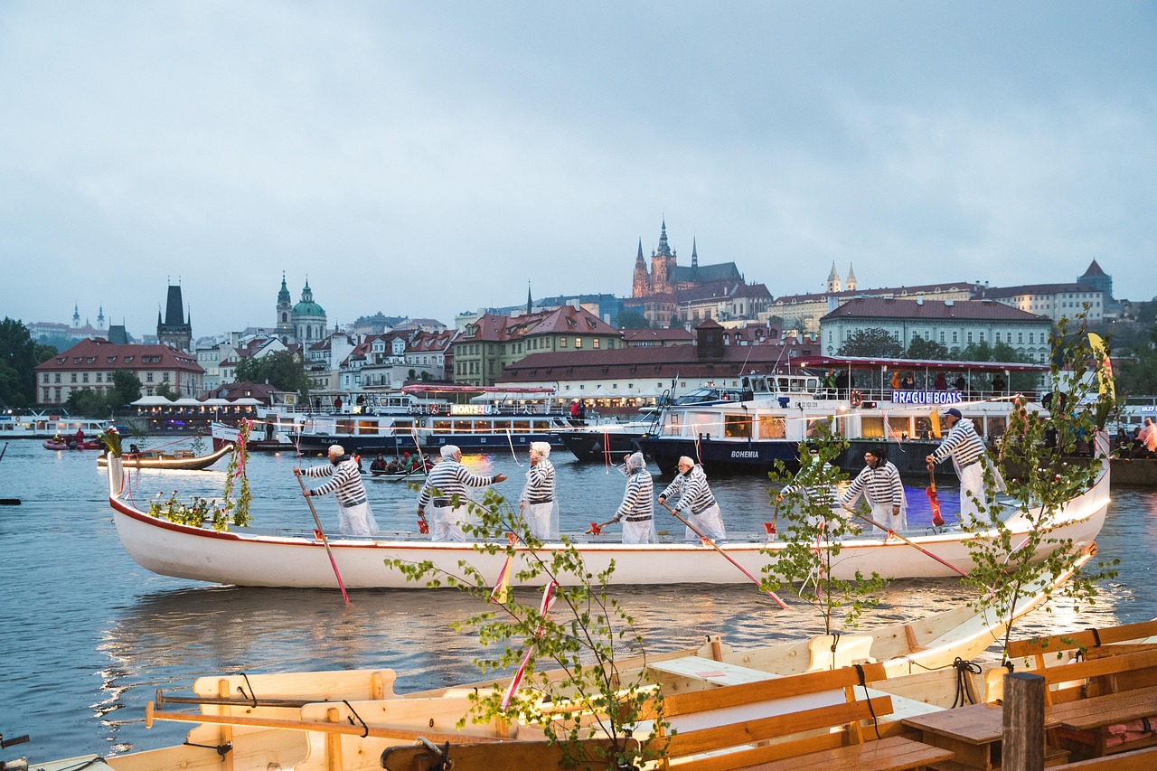 Boats on the Vltava River at dusk with Prague's illuminated riverbanks