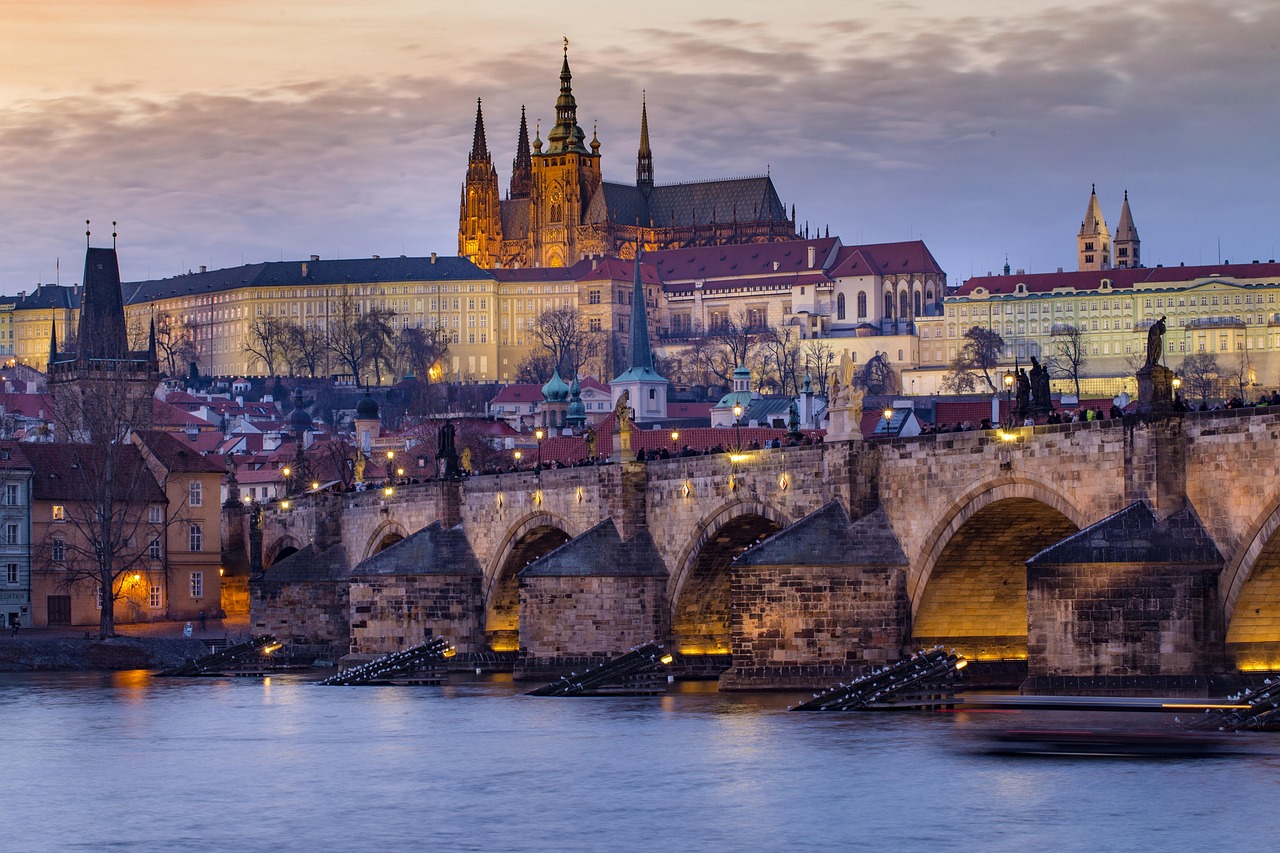 Prague Castle with bridge and river at sunset with city buildings