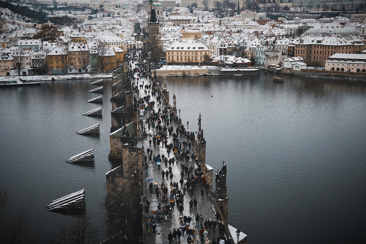 Crowds walking across Charles Bridge in Prague with towers visible