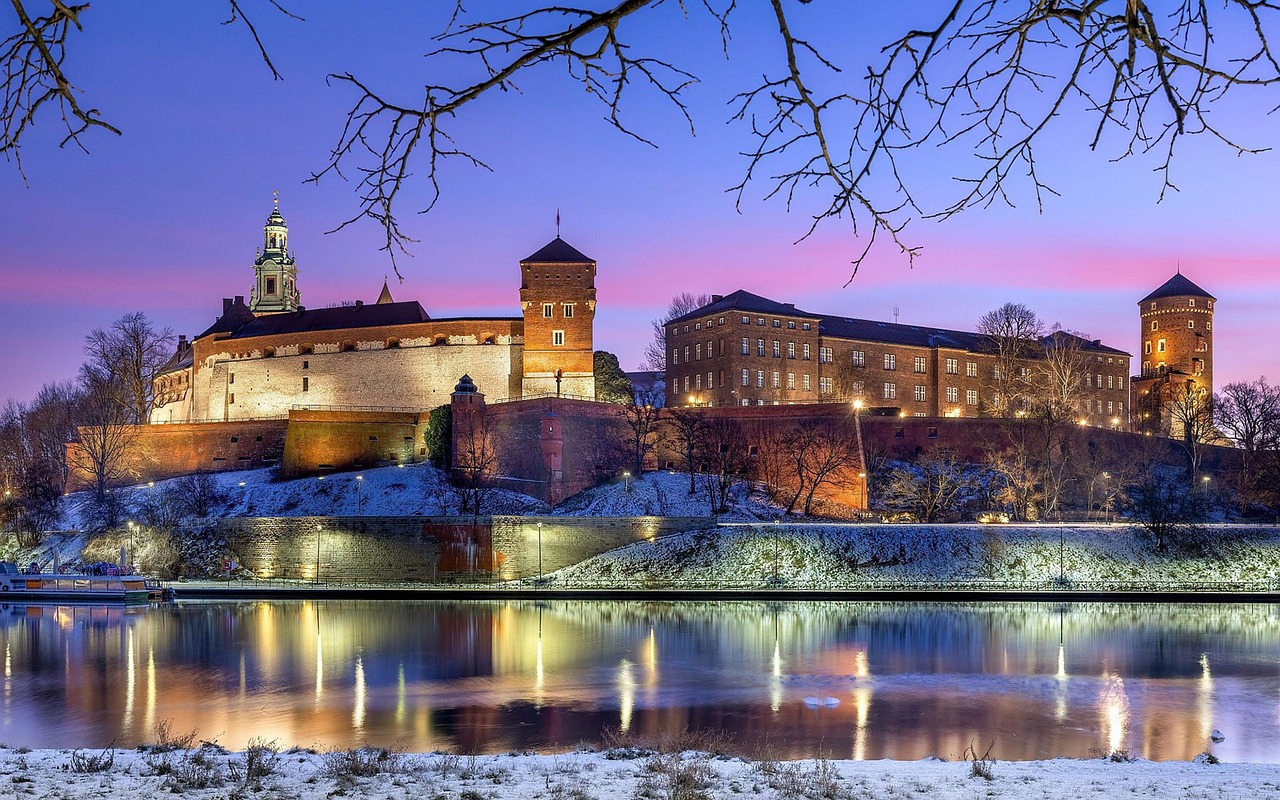 Wawel Royal Castle illuminated at dusk with reflections in the Vistula River
