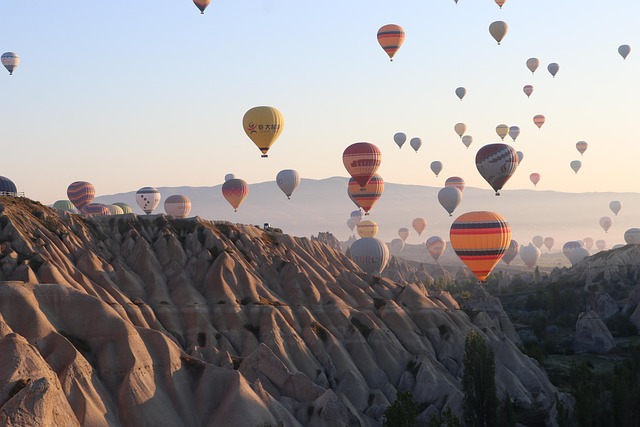 Hot air balloons floating above the Cappadocia landscape at sunrise with fairy chimneys below