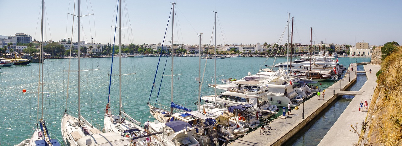 Yachts and sailboats lined up in Kos marina with mountains in the background
