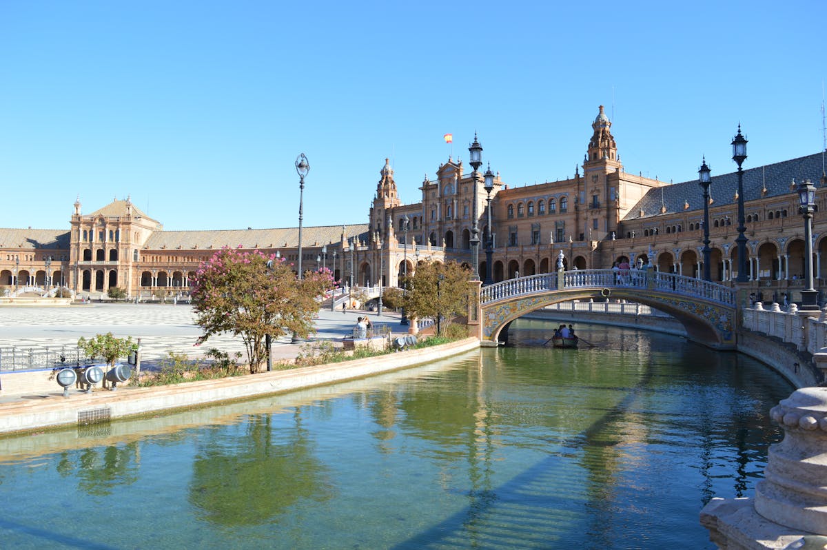 Bridge over a tranquil canal at Plaza de Espana in Seville with ornate architecture