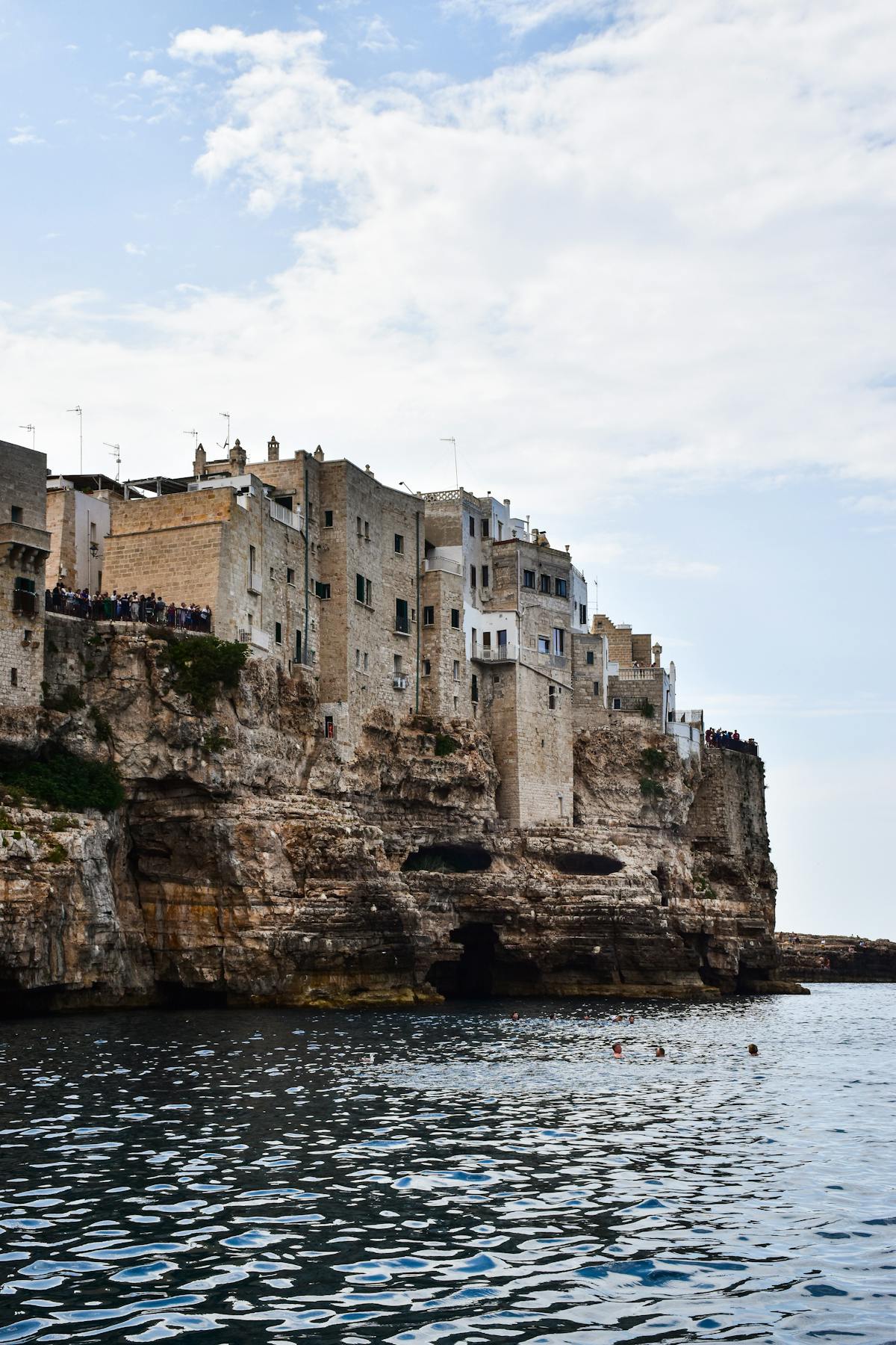 White cliffside buildings perched above the turquoise Adriatic Sea in Polignano a Mare Italy