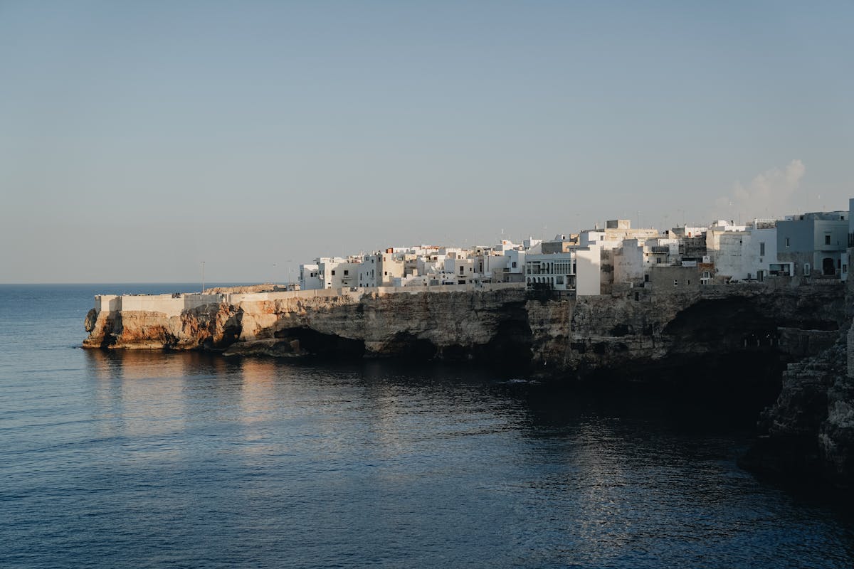 White cliffside houses and terraces looking out over the clear blue sea in Polignano a Mare