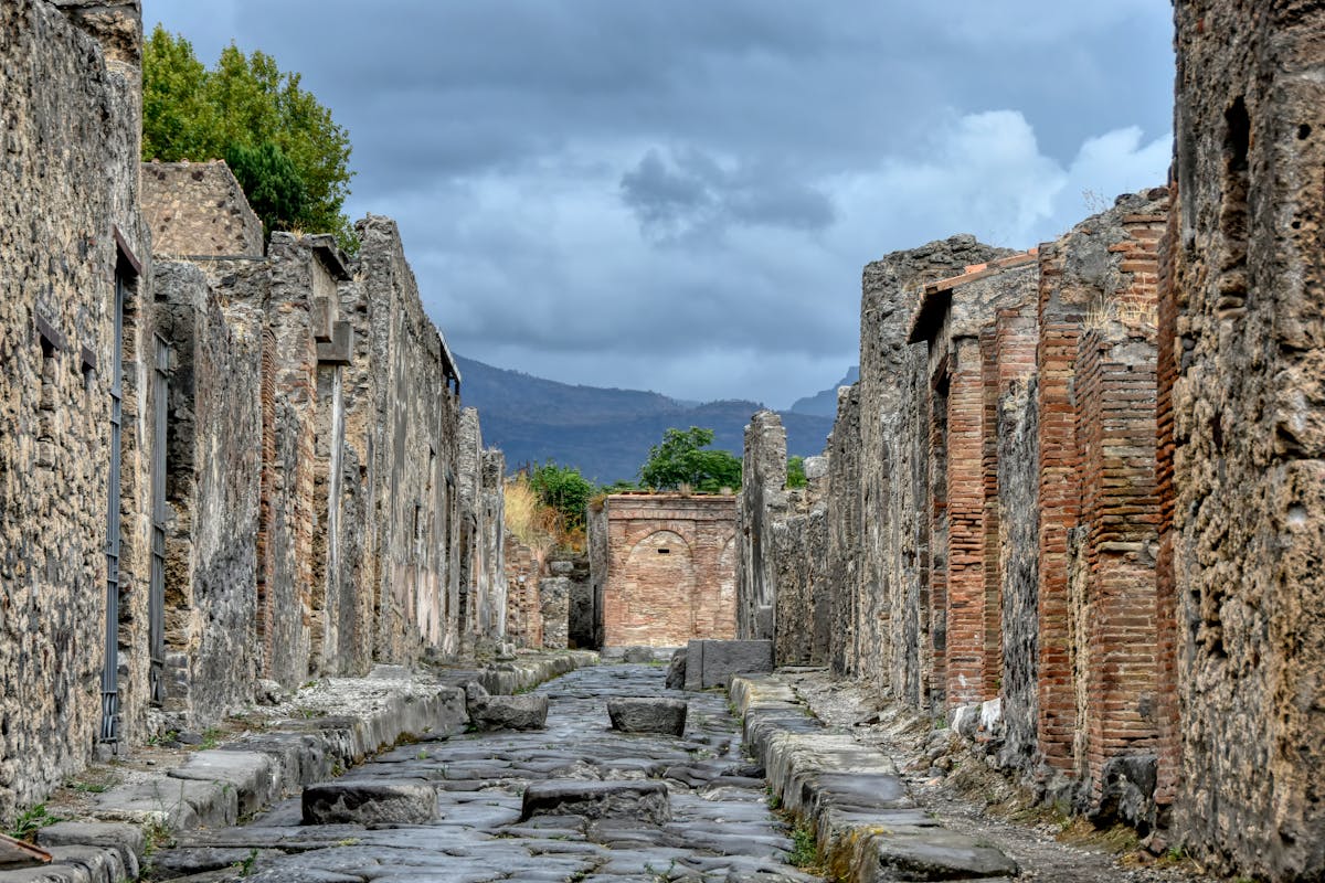 Ancient stone ruins and streets of Pompeii with distant mountains under a cloudy sky