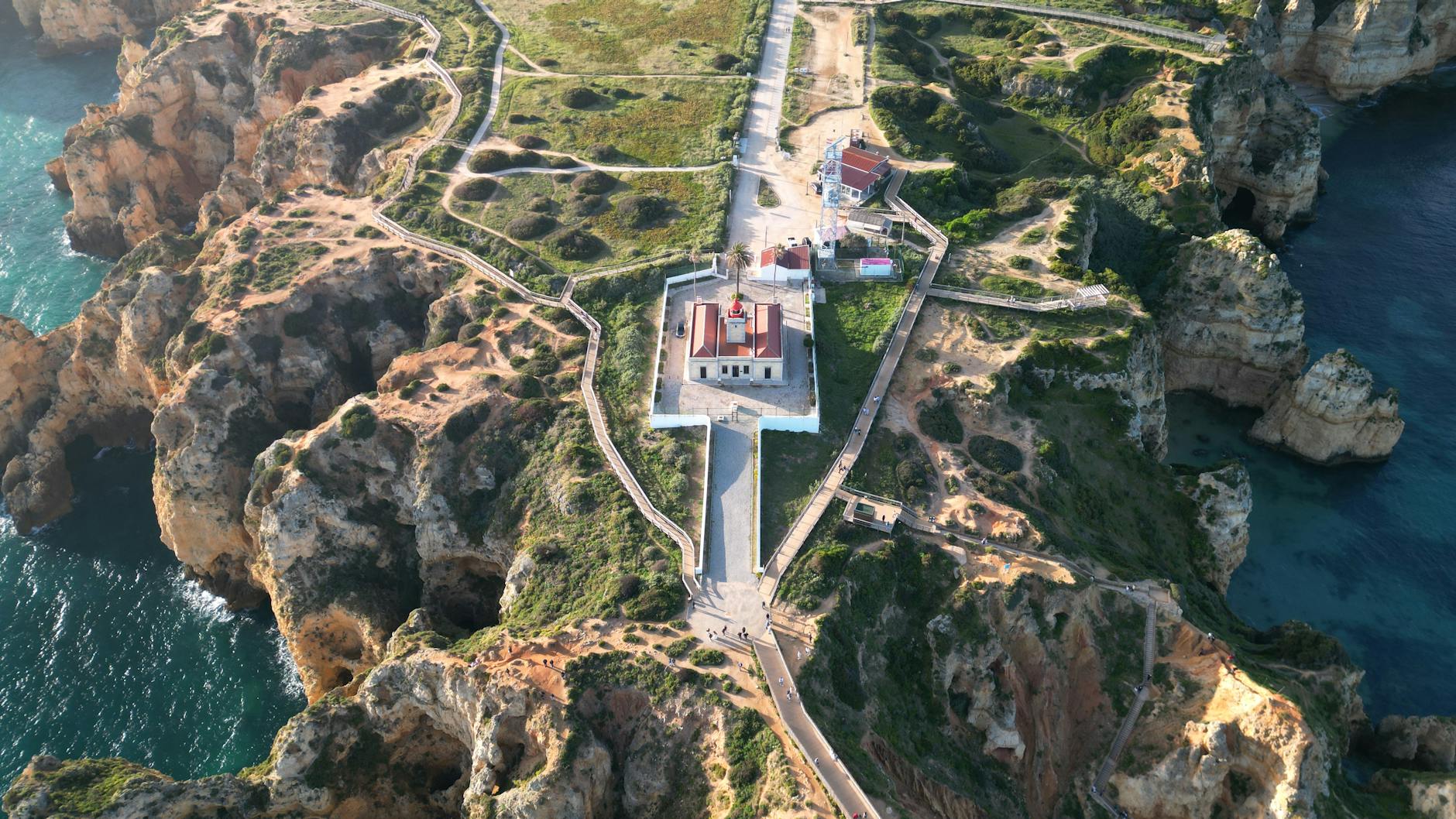 Aerial view of the Ponta da Piedade lighthouse perched above golden limestone cliffs with turquoise water below