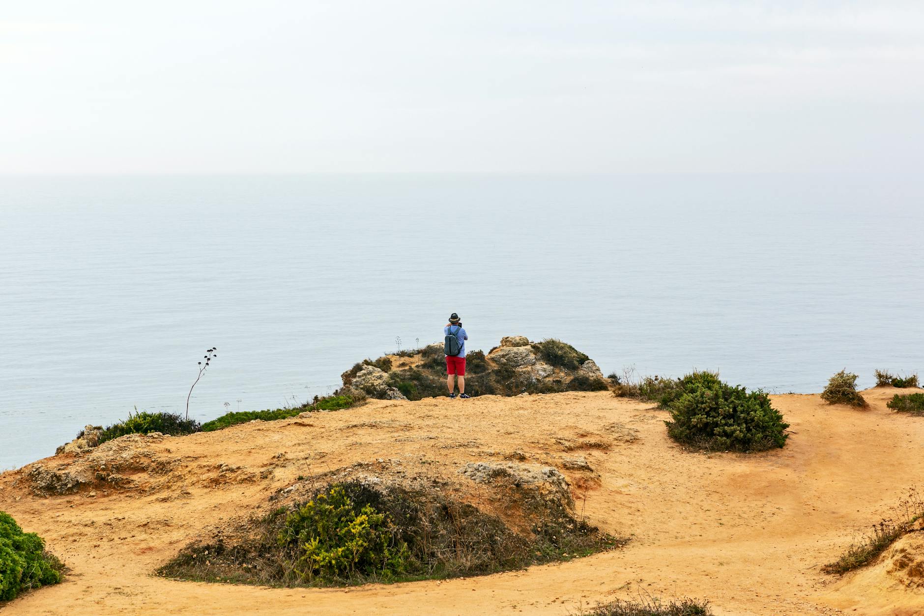 Person standing on dramatic sea cliffs overlooking the ocean near Lagos Portugal