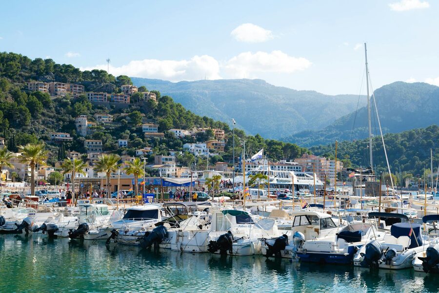 Boats moored in Port de Soller harbour with hillside houses behind