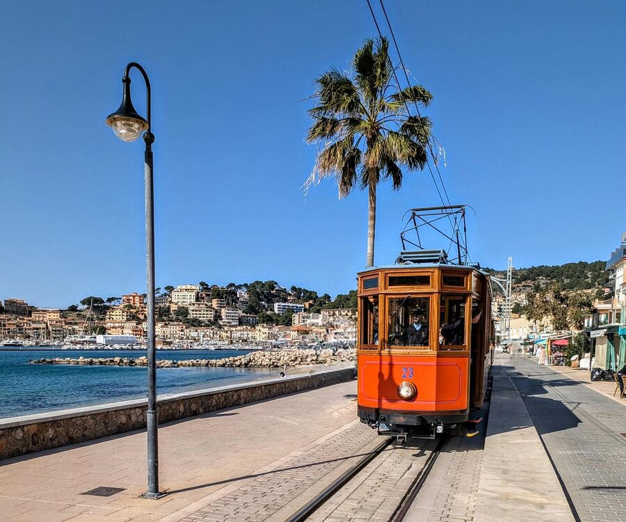 Red tram running along the Port de Soller waterfront promenade