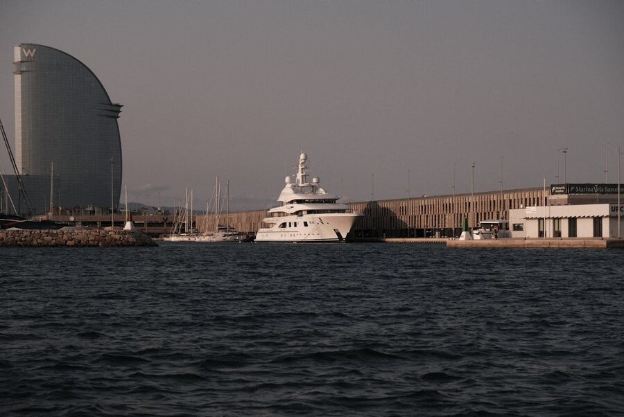 Yacht docked at Port Vell Barcelona with W Hotel in backdrop at sunset