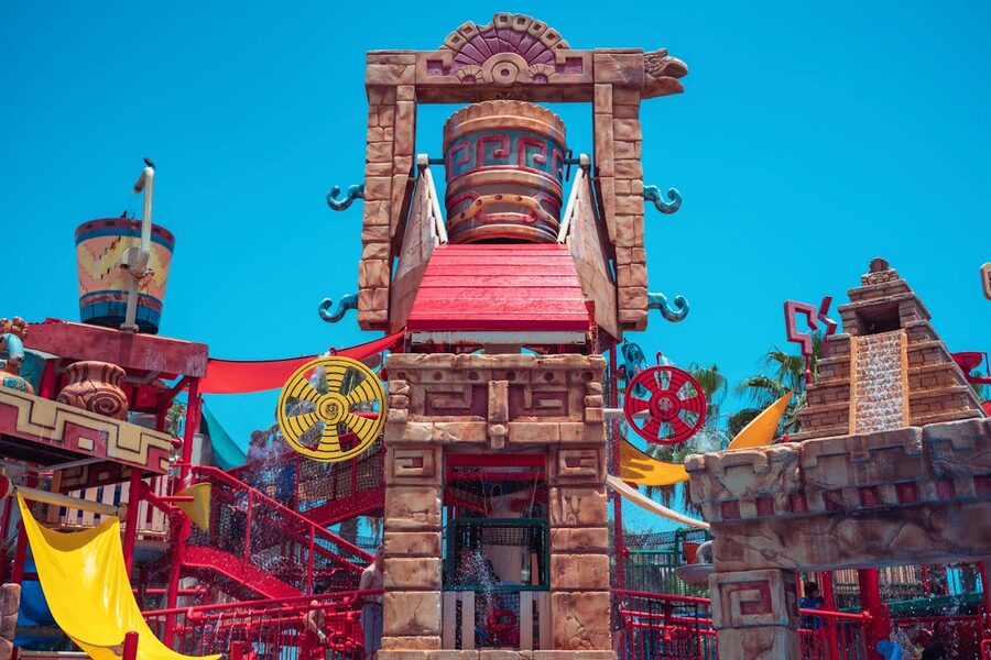 Aztec themed stone structures at colorful water park under blue sky