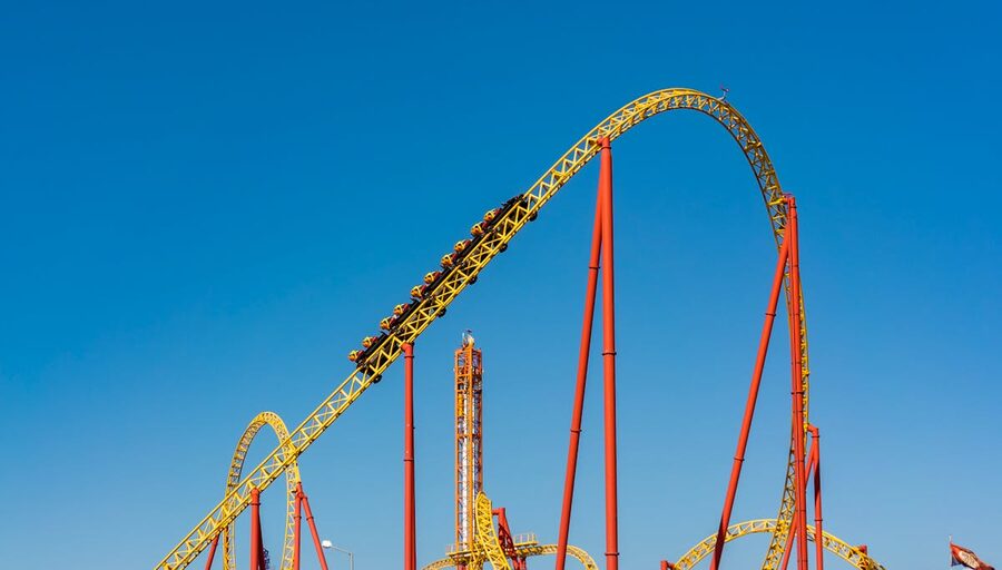 Steel roller coaster track curving against clear blue sky