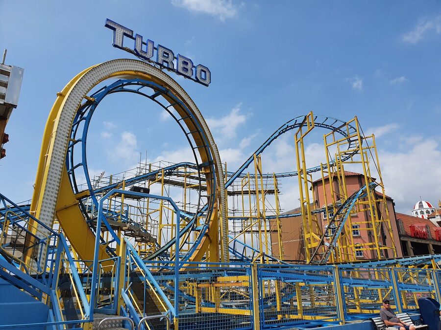 Dynamic colorful roller coaster against clear blue sky
