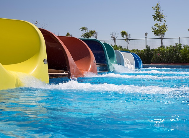 Person sliding down colourful water slide at outdoor aquatic park
