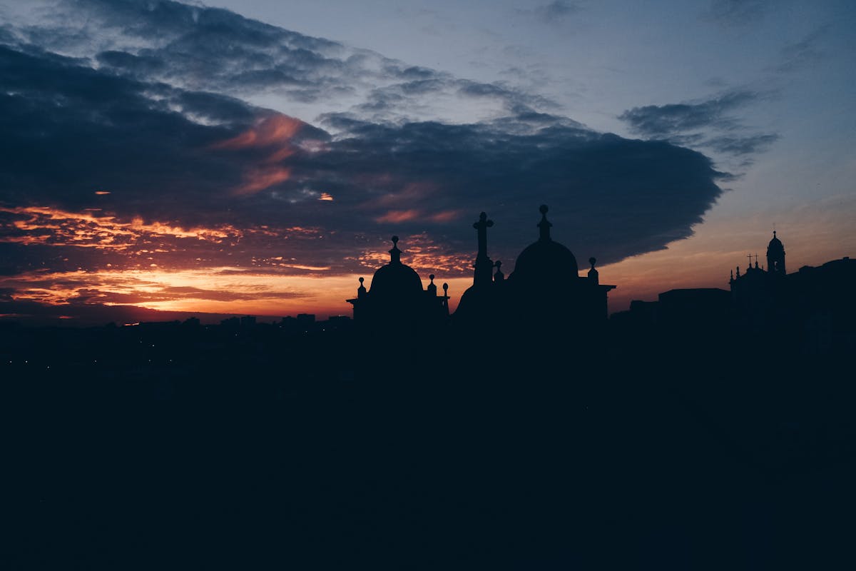 Silhouettes of Porto church domes against a dramatic orange sunset sky
