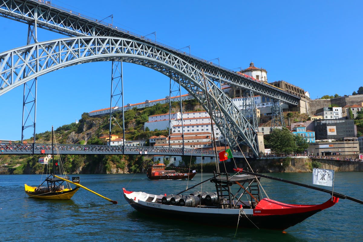 Dom Luis I Bridge spanning the Douro River in Porto with traditional boats in the foreground