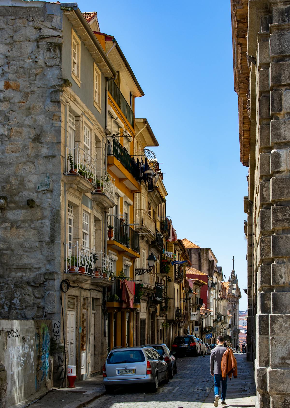 Scenic narrow cobblestone street in Porto lined with historic buildings on a sunny day