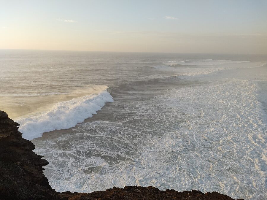 Praia do Norte Nazare with surfer at sunset