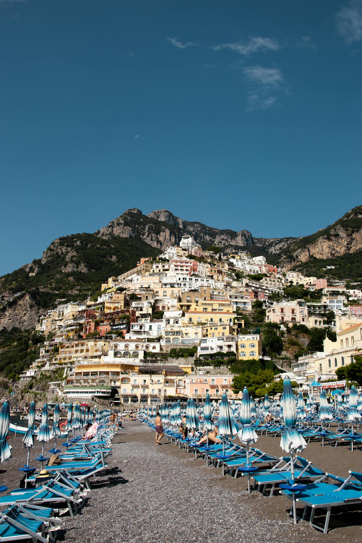 Beach and town view of Positano with colorful buildings under blue sky