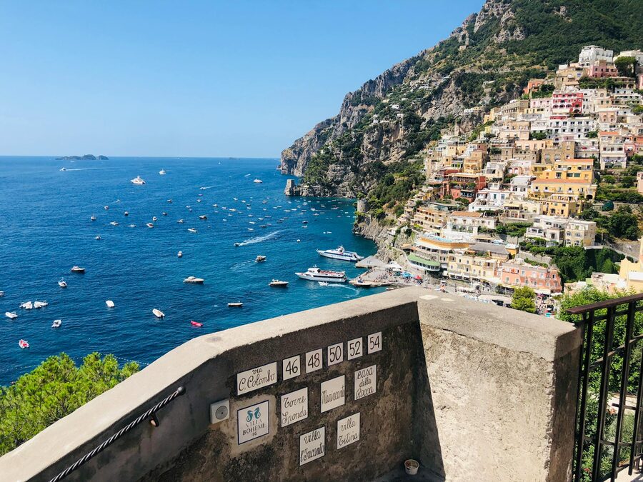 Positano beach and town view from the water with colorful buildings rising up the hillside