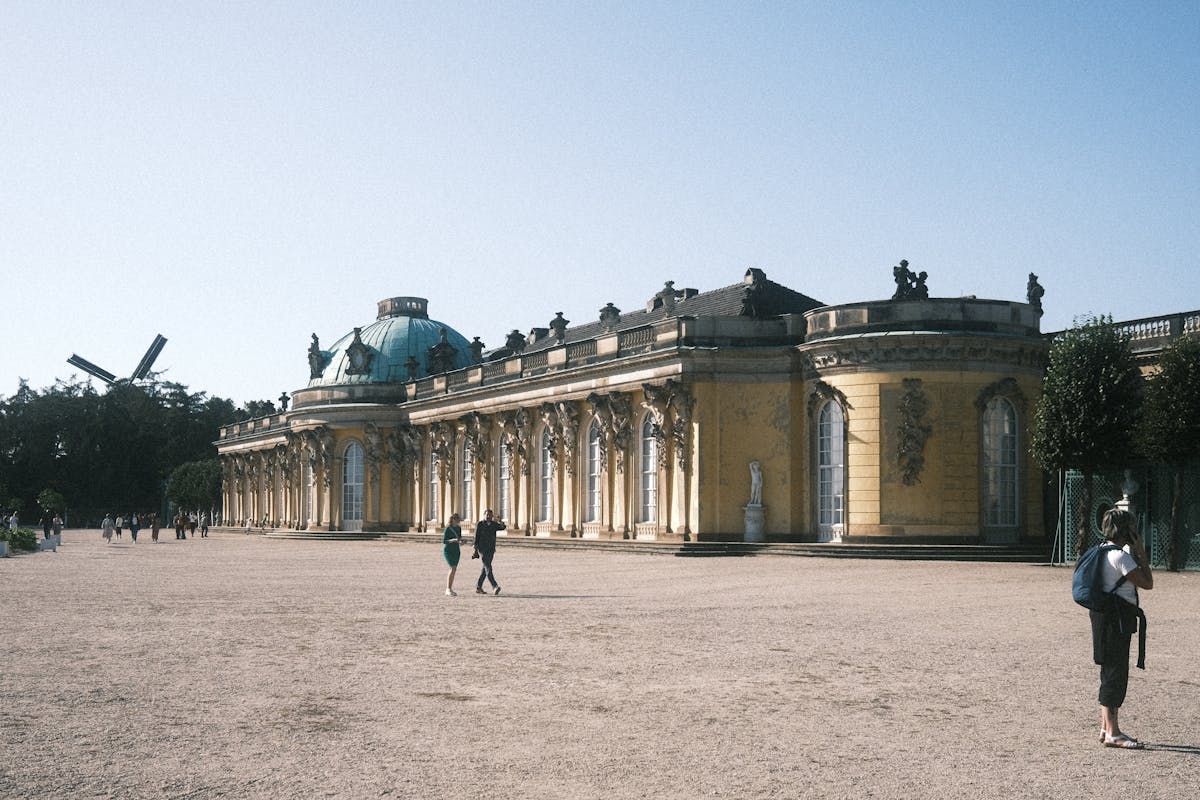 People walking at Sanssouci Palace under clear blue sky