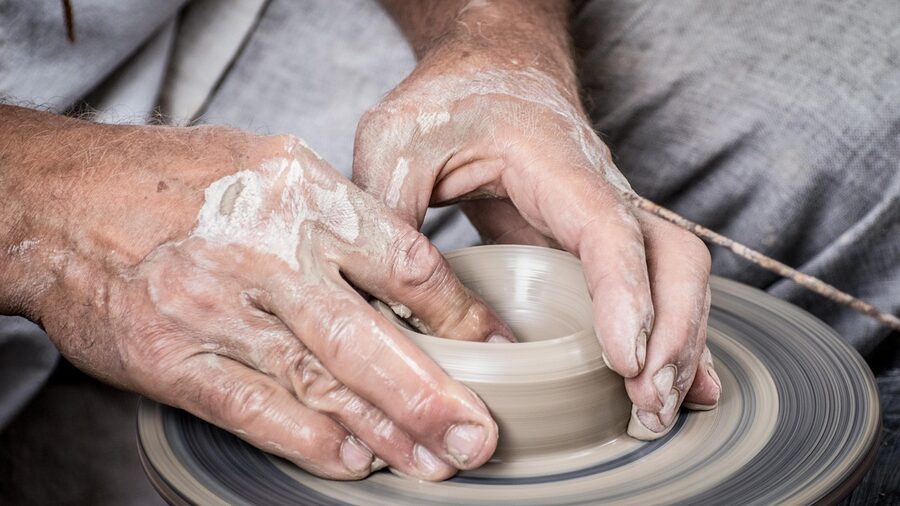 Hands shaping clay on a pottery wheel in a craft workshop