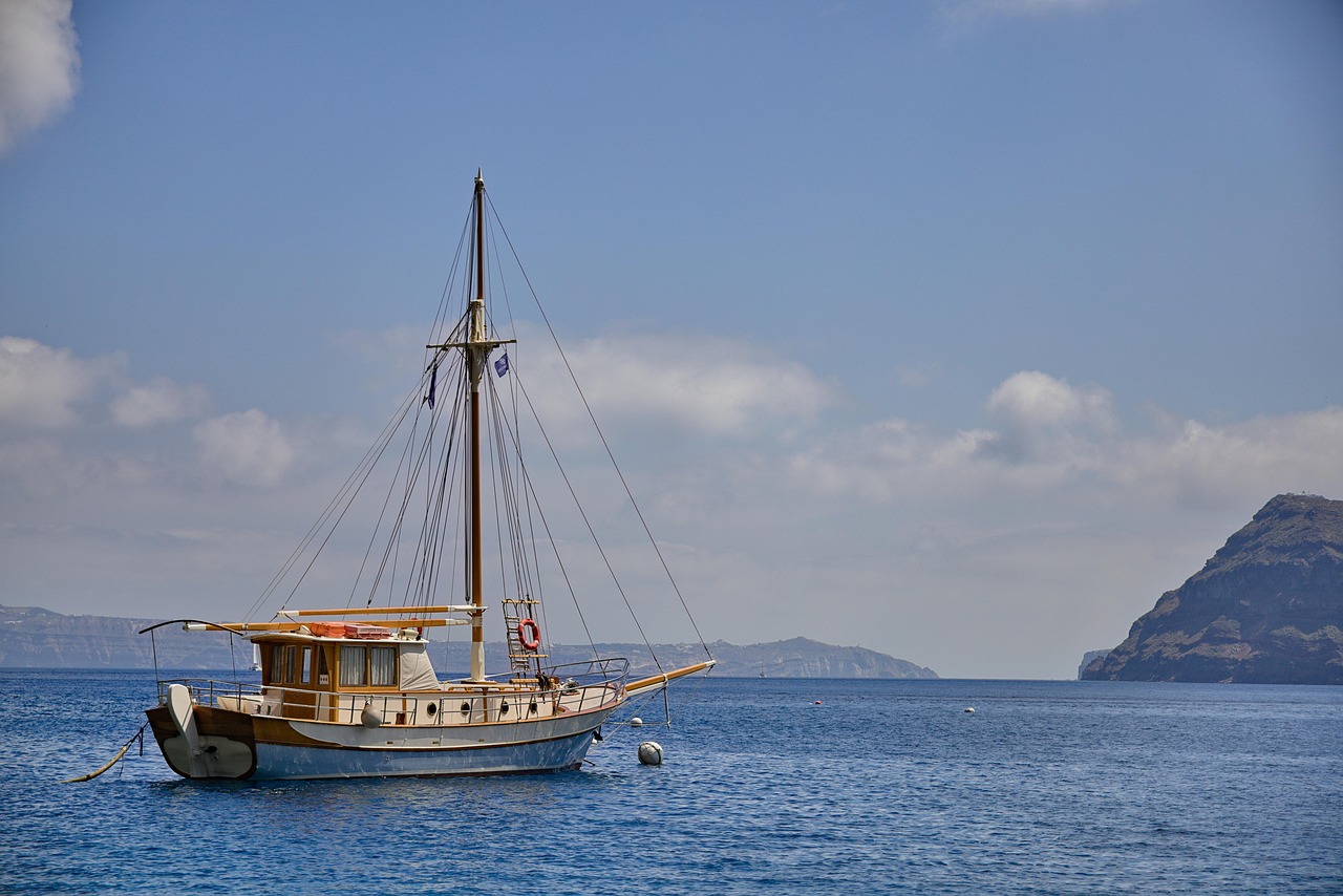 Sailboat crossing the Santorini caldera with volcanic islands behind