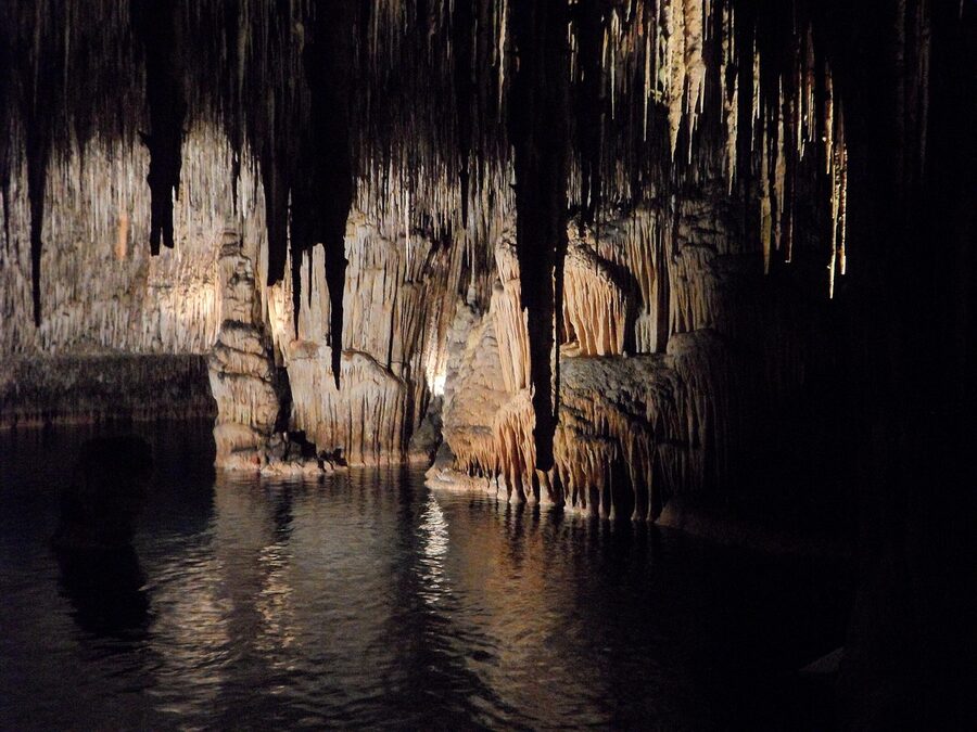 Walking pathway through an illuminated underground cave with stalactites