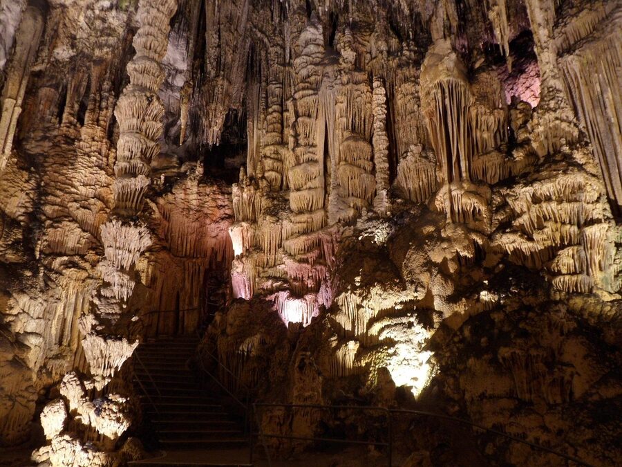 Tall stalactite formations hanging from the ceiling of an underground cavern