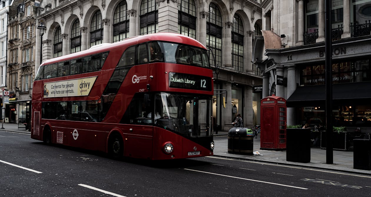 Red double-decker bus on a historic London street with traditional architecture