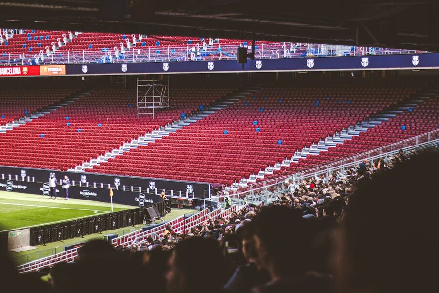 Red stadium seats with a crowd gathered for a live football match