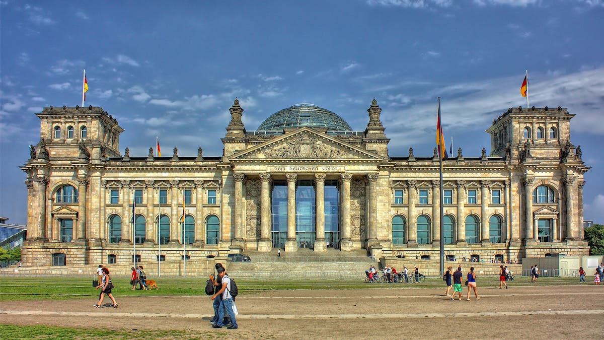 Visitors in front of the Reichstag building on a bright day